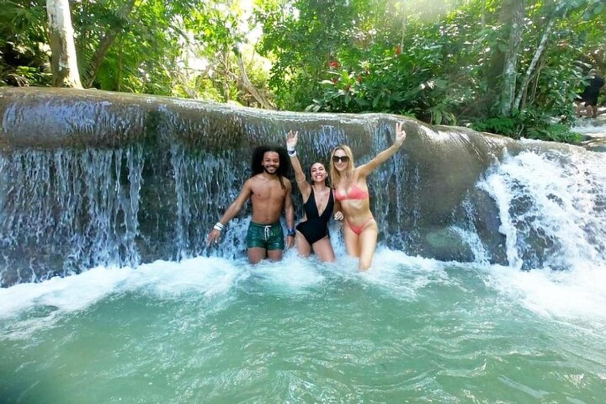 três pessoas em pé em frente a uma cachoeira
