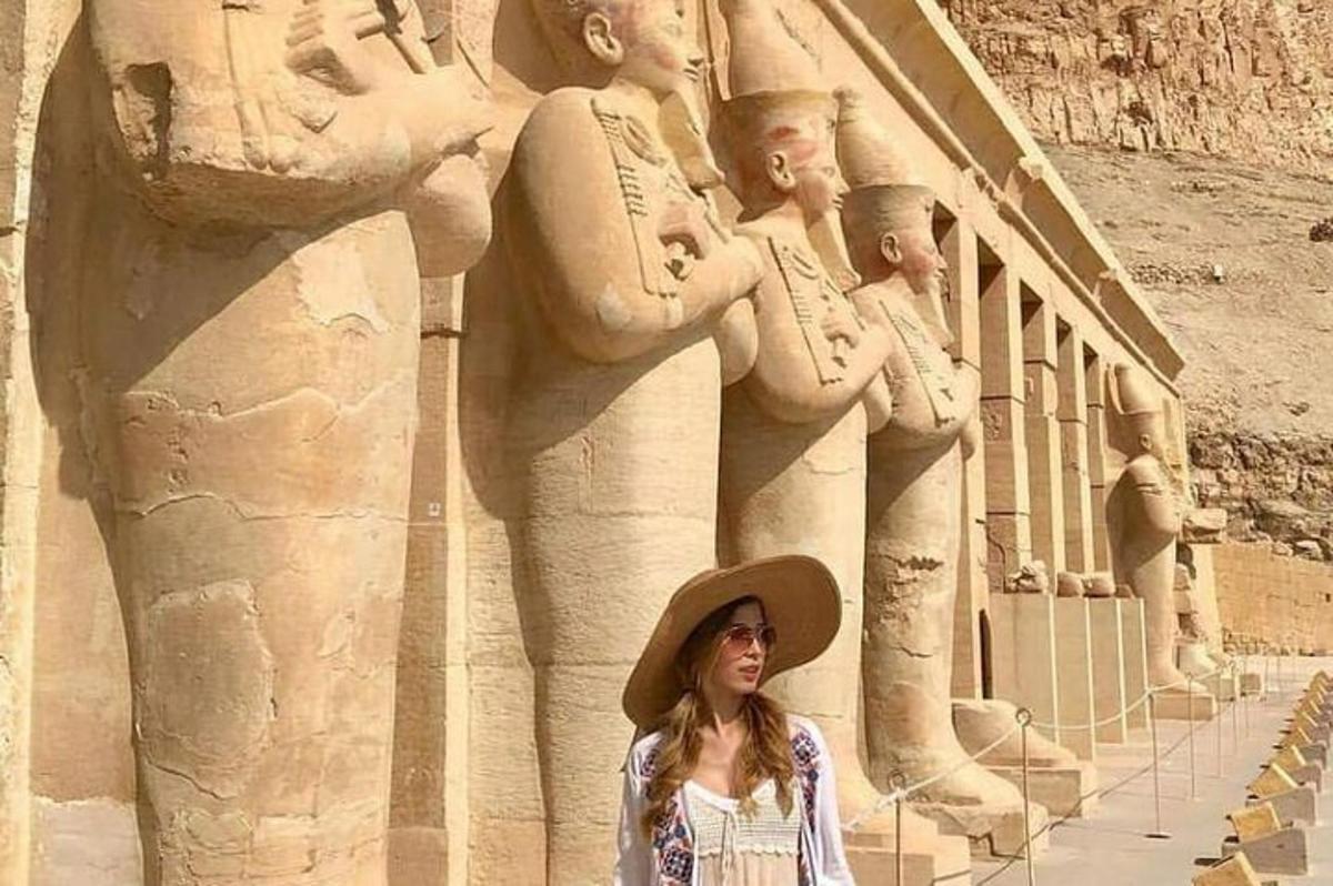 모자를 쓴 여성이 동상 앞에 서 있다