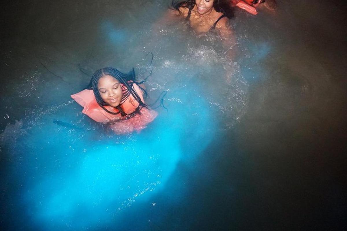 una bambina sdraiata nell'acqua con un ombrello