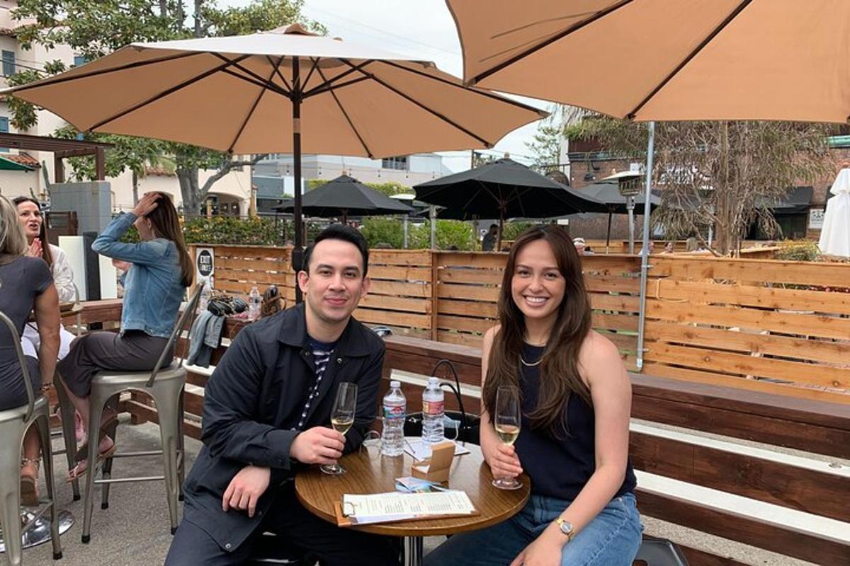 um homem e uma mulher sentados à mesa com taças de vinho