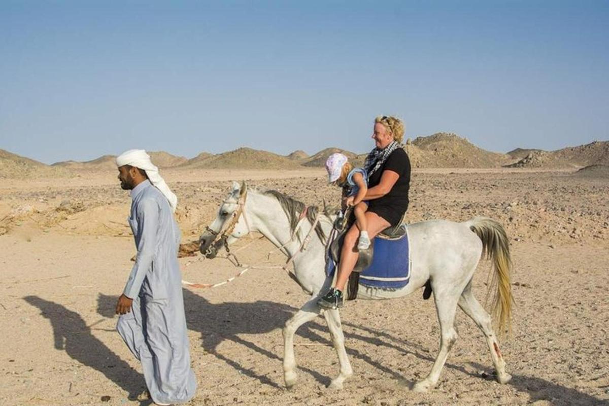 ein Mann und eine Frau reiten auf einem Pferd in der Wüste