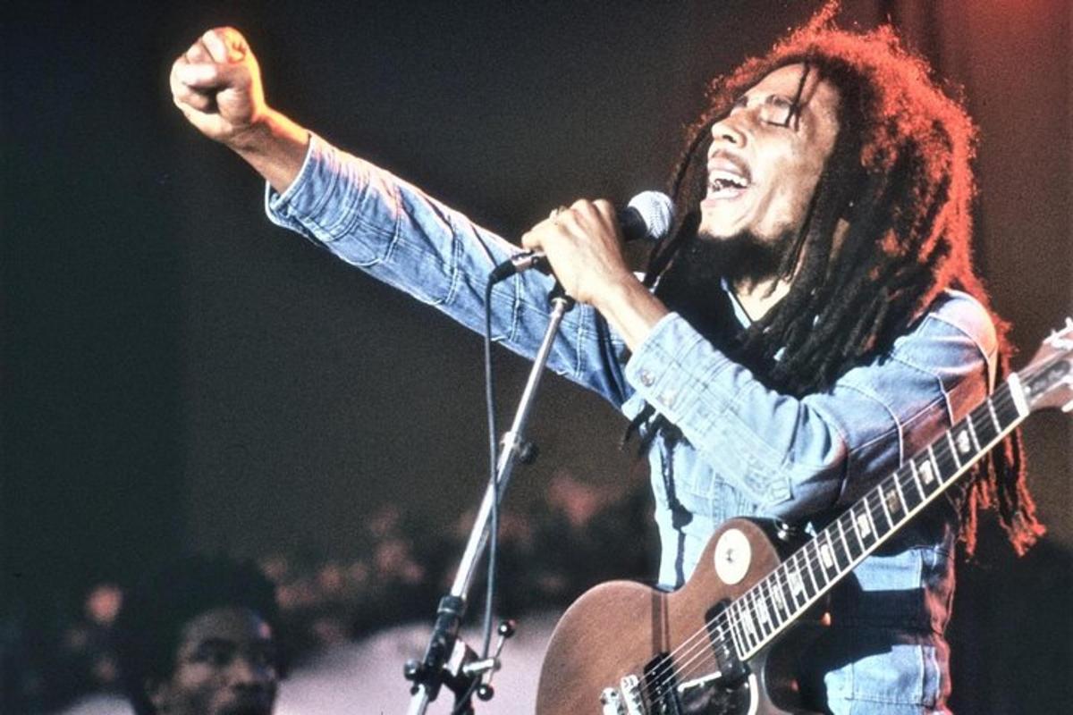 a man with long hair playing a guitar with a microphone