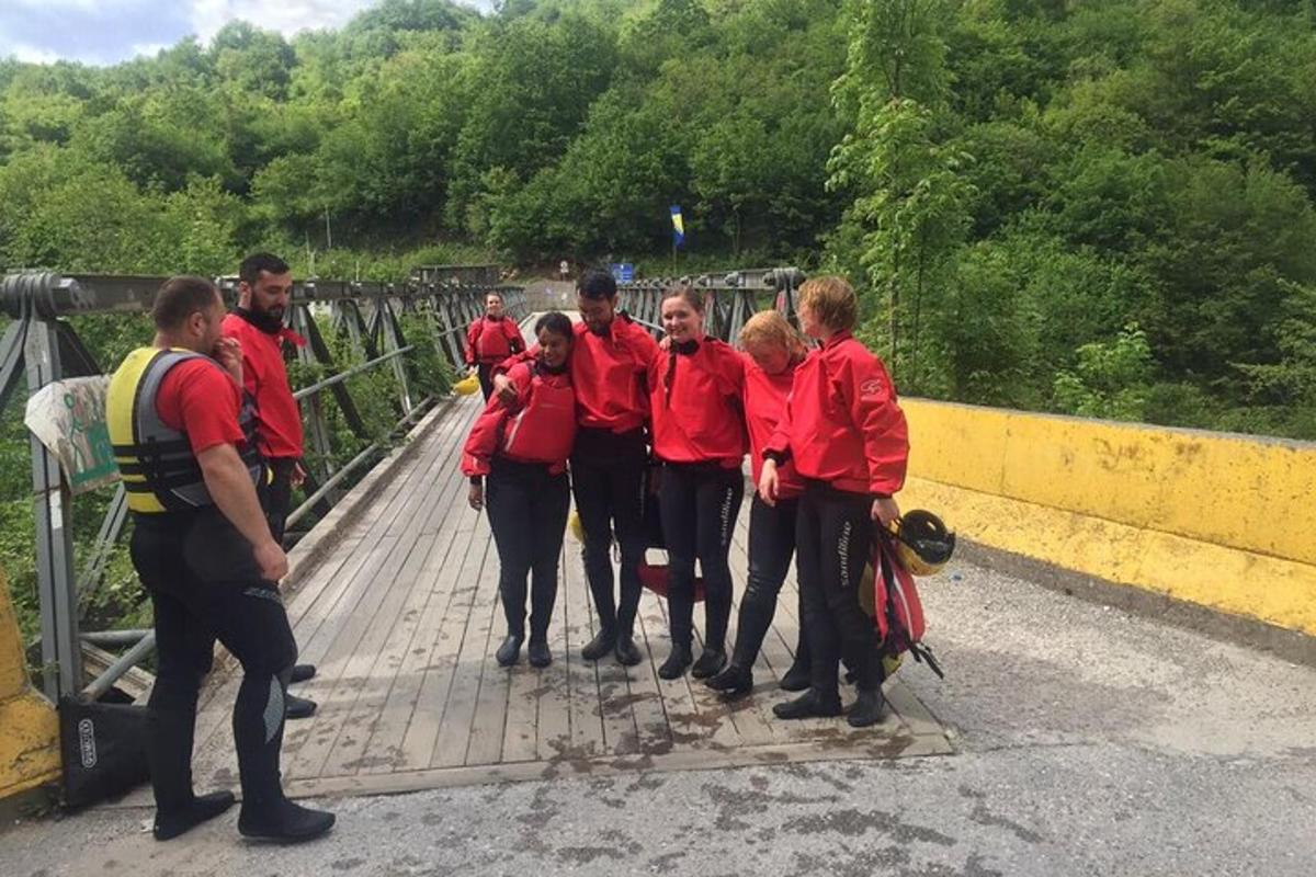 skupina ljudi v rdečih jaknah, ki stojijo na mostu