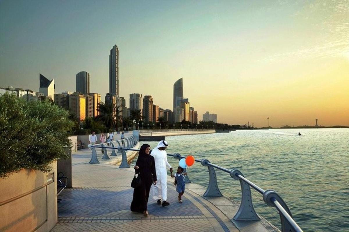 a group of people walking on a sidewalk near the water