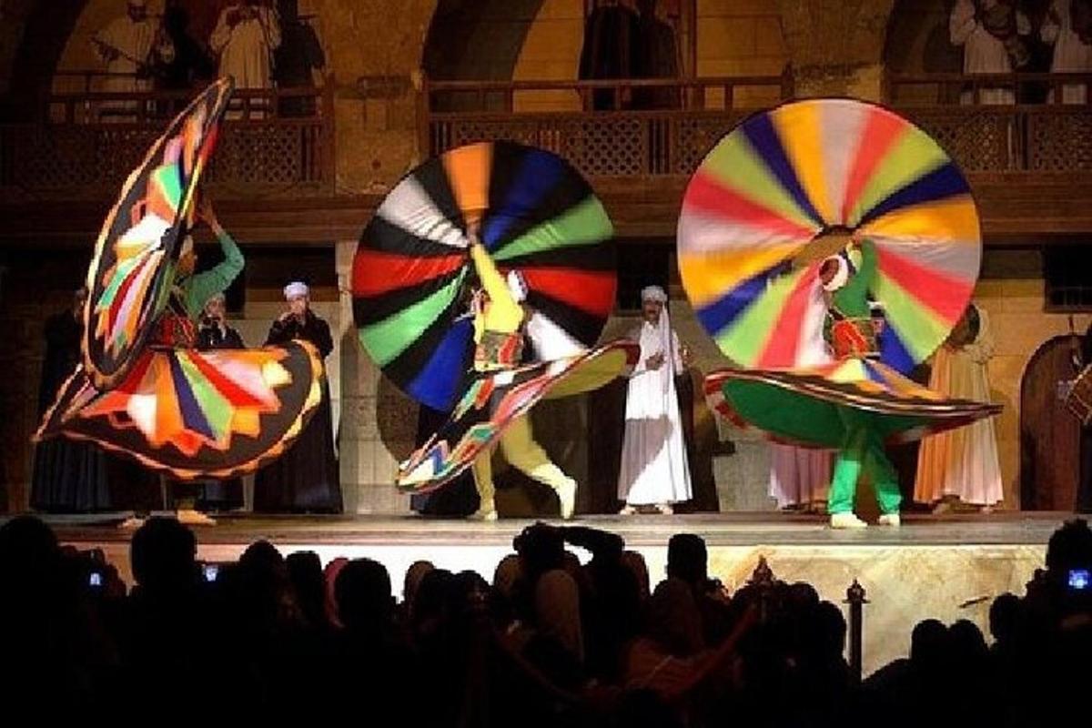 a group of people watching people on a stage with umbrellas