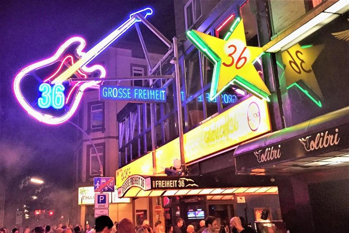 a crowd of people standing outside of a building with neon signs
