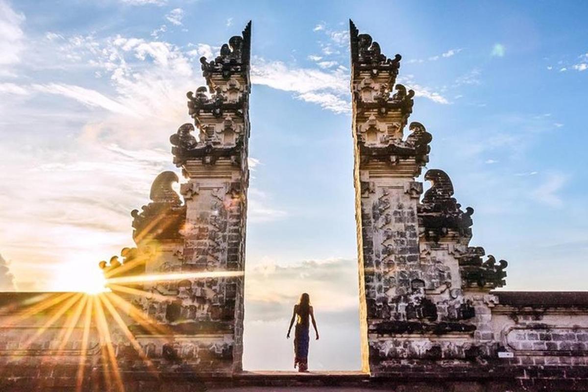 seorang wanita berdiri di ambang pintu gerbang saat matahari terbenam