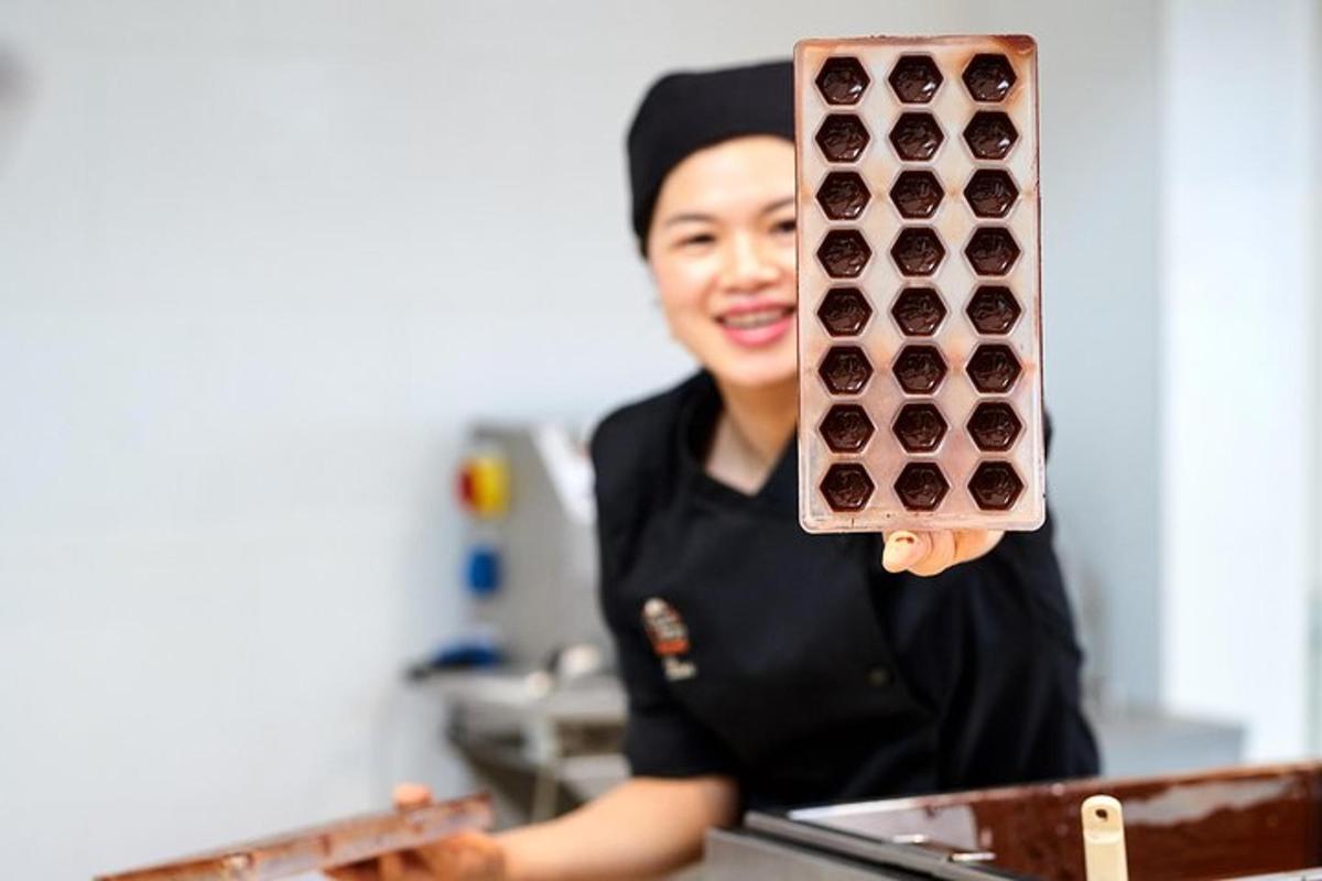 a woman in a kitchen holding a tray of cupcakes