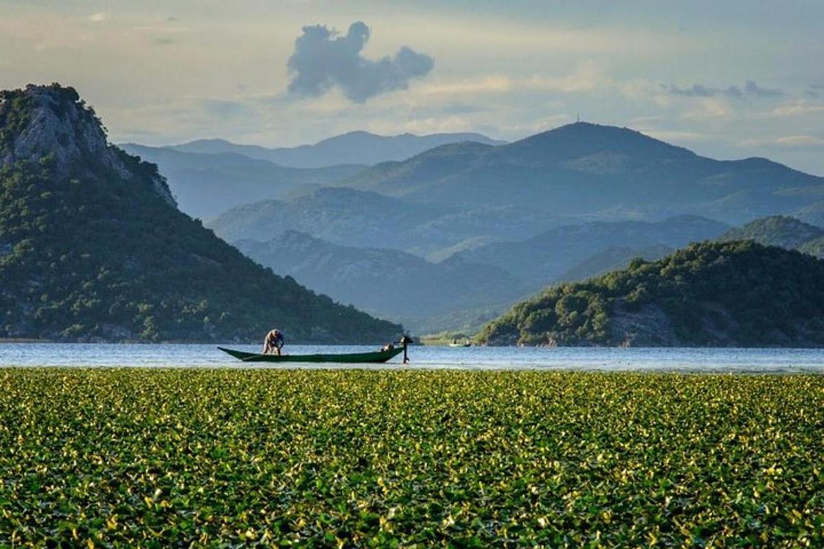 um homem em um barco na água com montanhas
