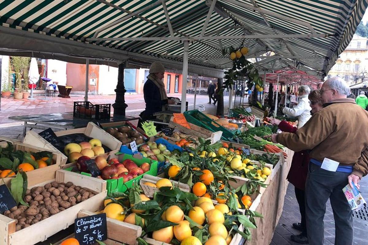 a group of people standing around a market with fruits and vegetables