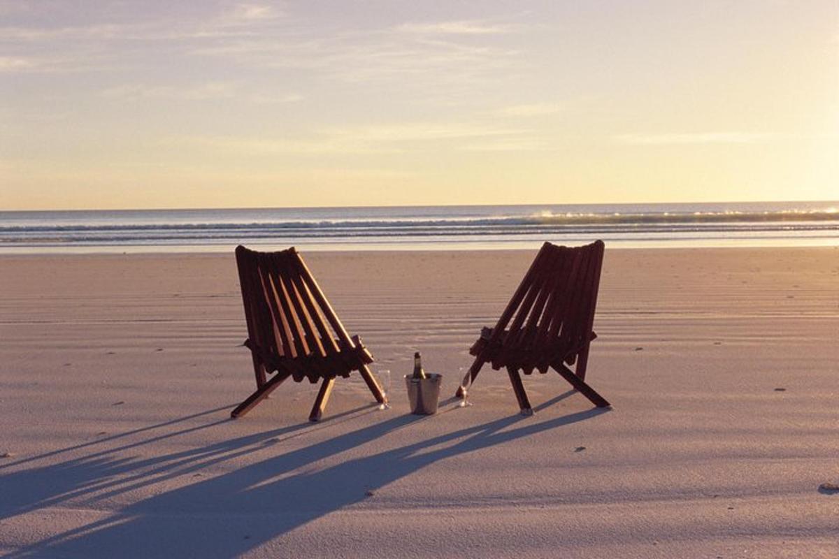two chairs sitting in the sand on a beach