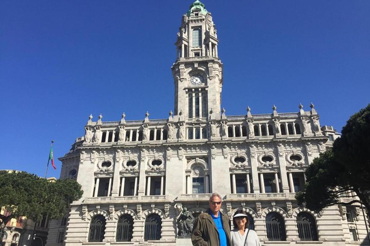 Dos personas de pie frente a un edificio con una torre de reloj.
