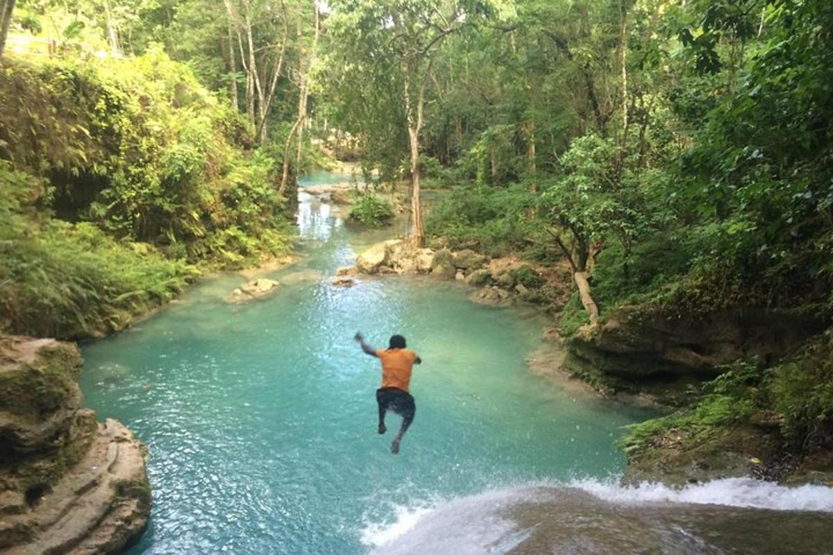 Ein Mann springt von einem Wasserfall in einen Fluss