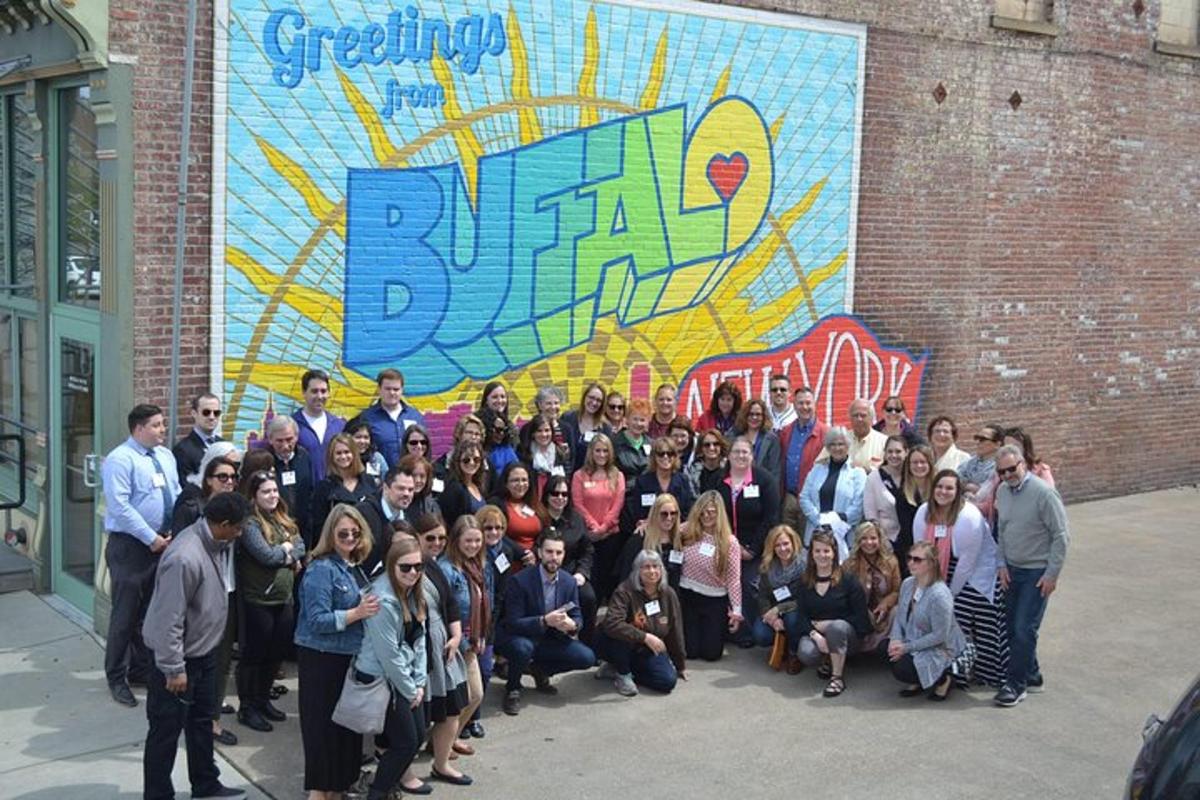 un gruppo di persone in posa per una foto davanti a un murale