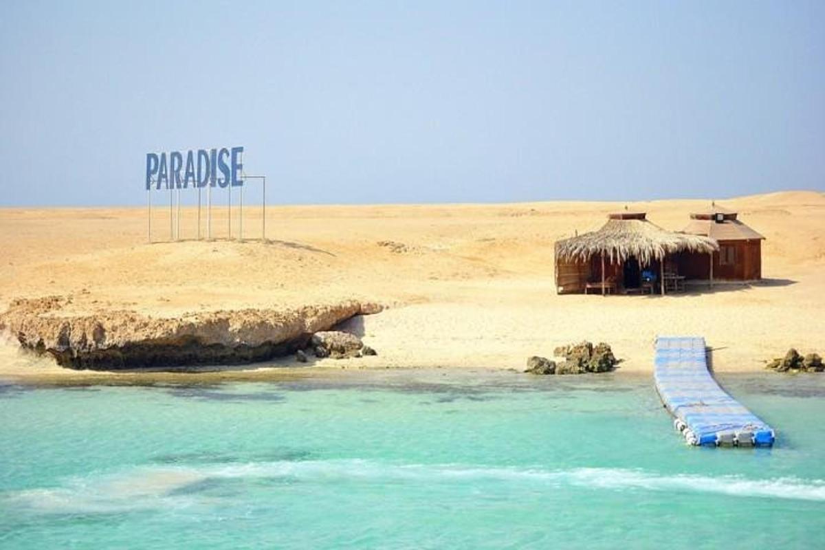 Una playa con cabañas y un cartel que dice paraíso.