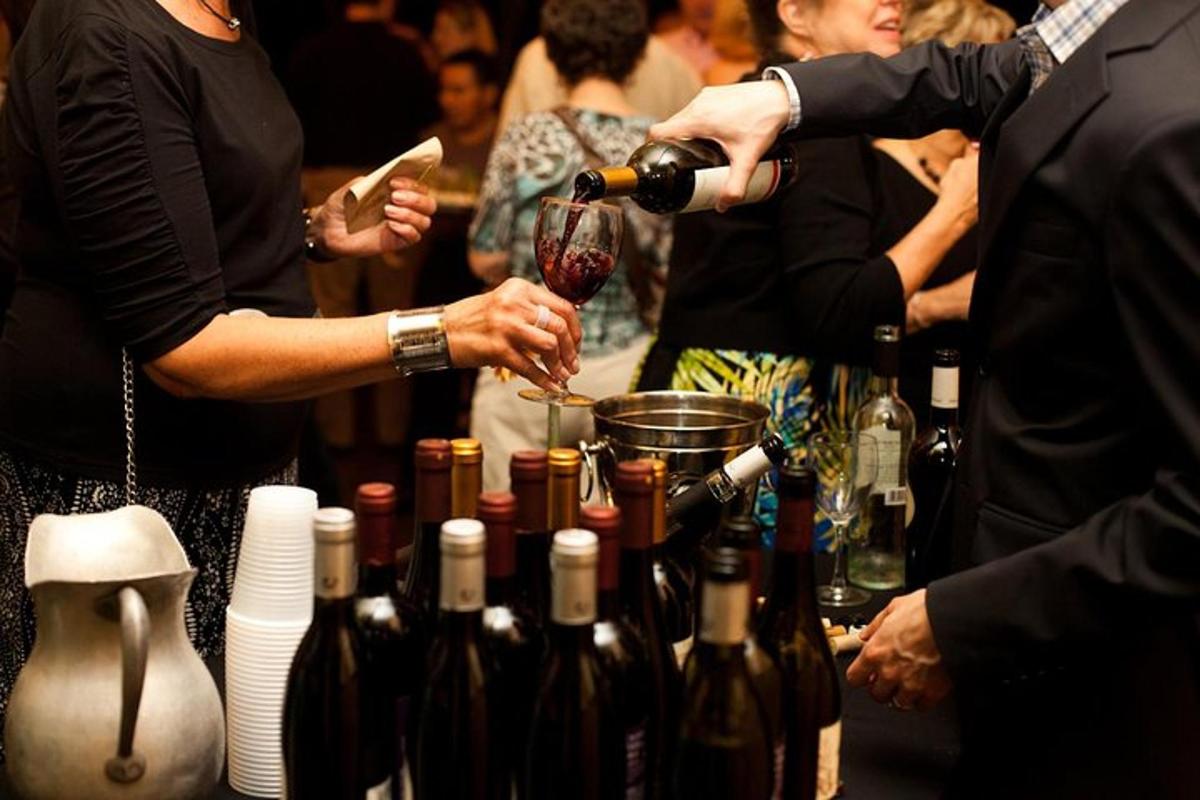 un grup de oameni care stau în jurul unei mese cu sticle de vin