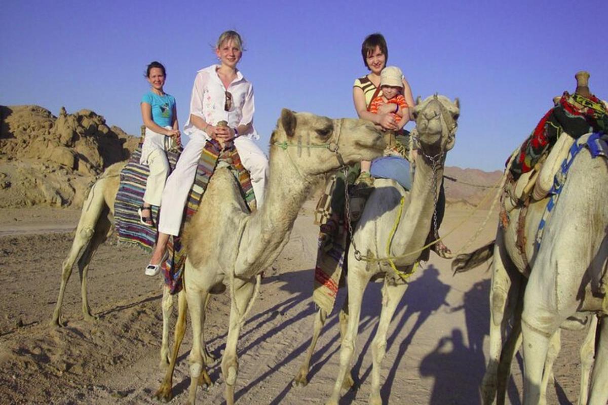 tres persones munten camells al desert