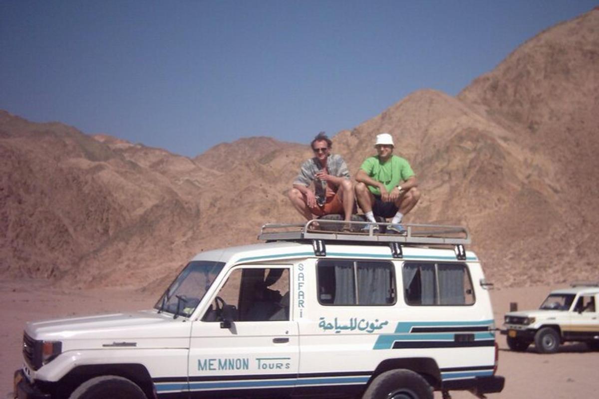 dos homes asseguts al sostre d'una furgoneta al desert