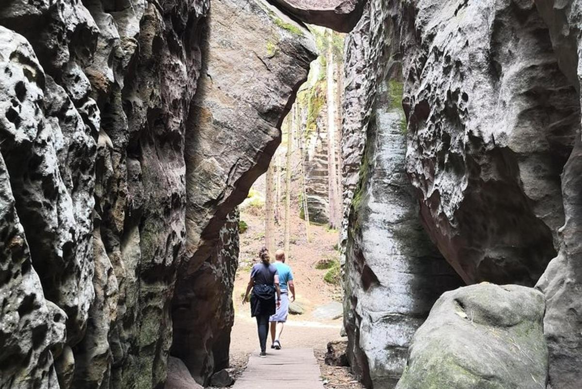 two people walking down a path through a rock wall