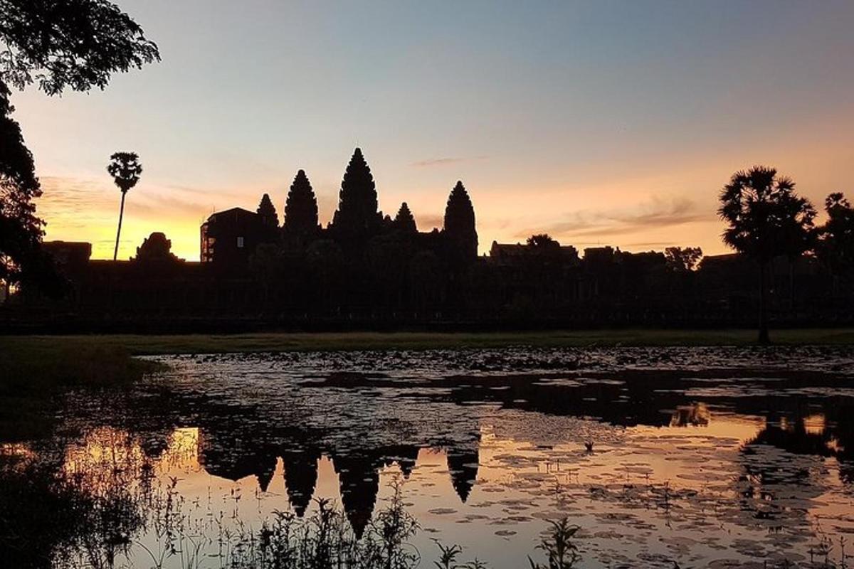 una posta de sol sobre un estany davant d'un temple