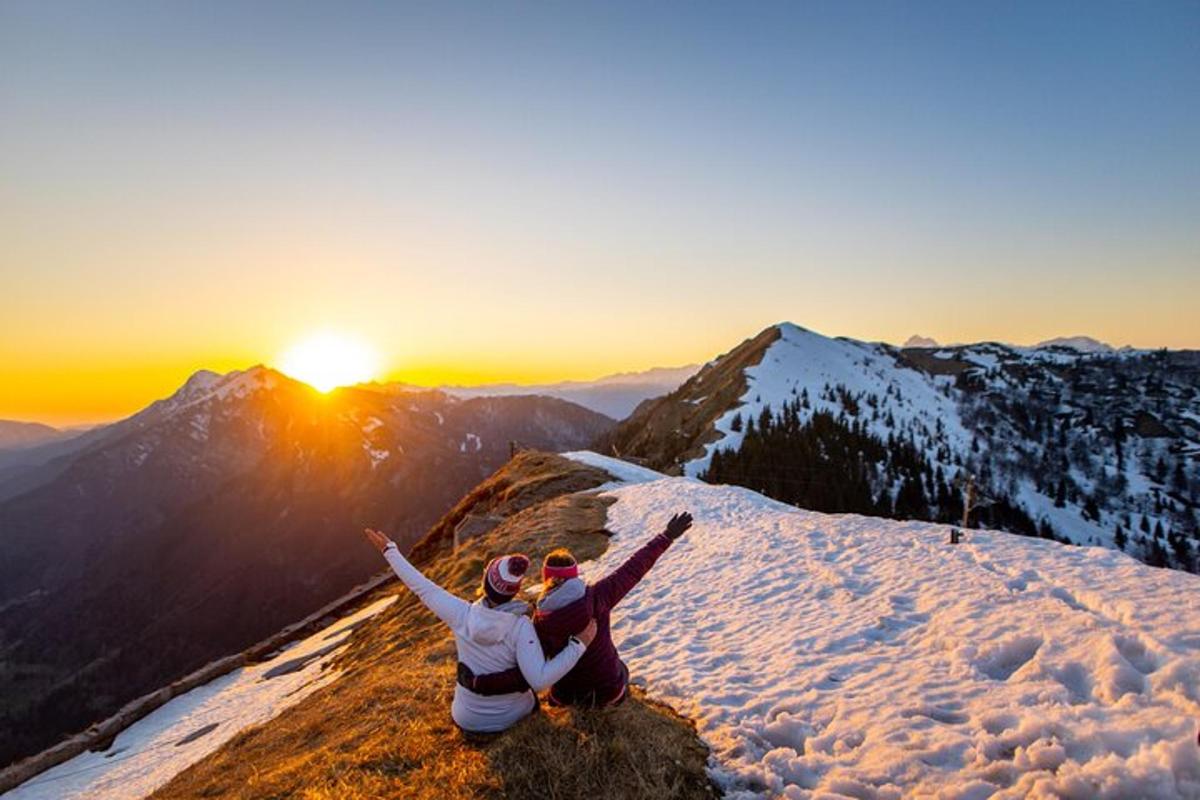 zwei Menschen sitzen mit erhobenen Armen auf einem Berggipfel