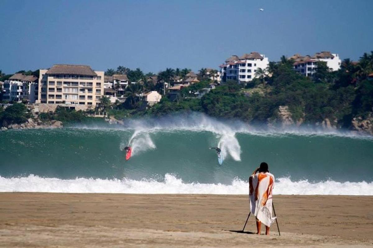 čovjek hoda plažom s daskom za surfanje