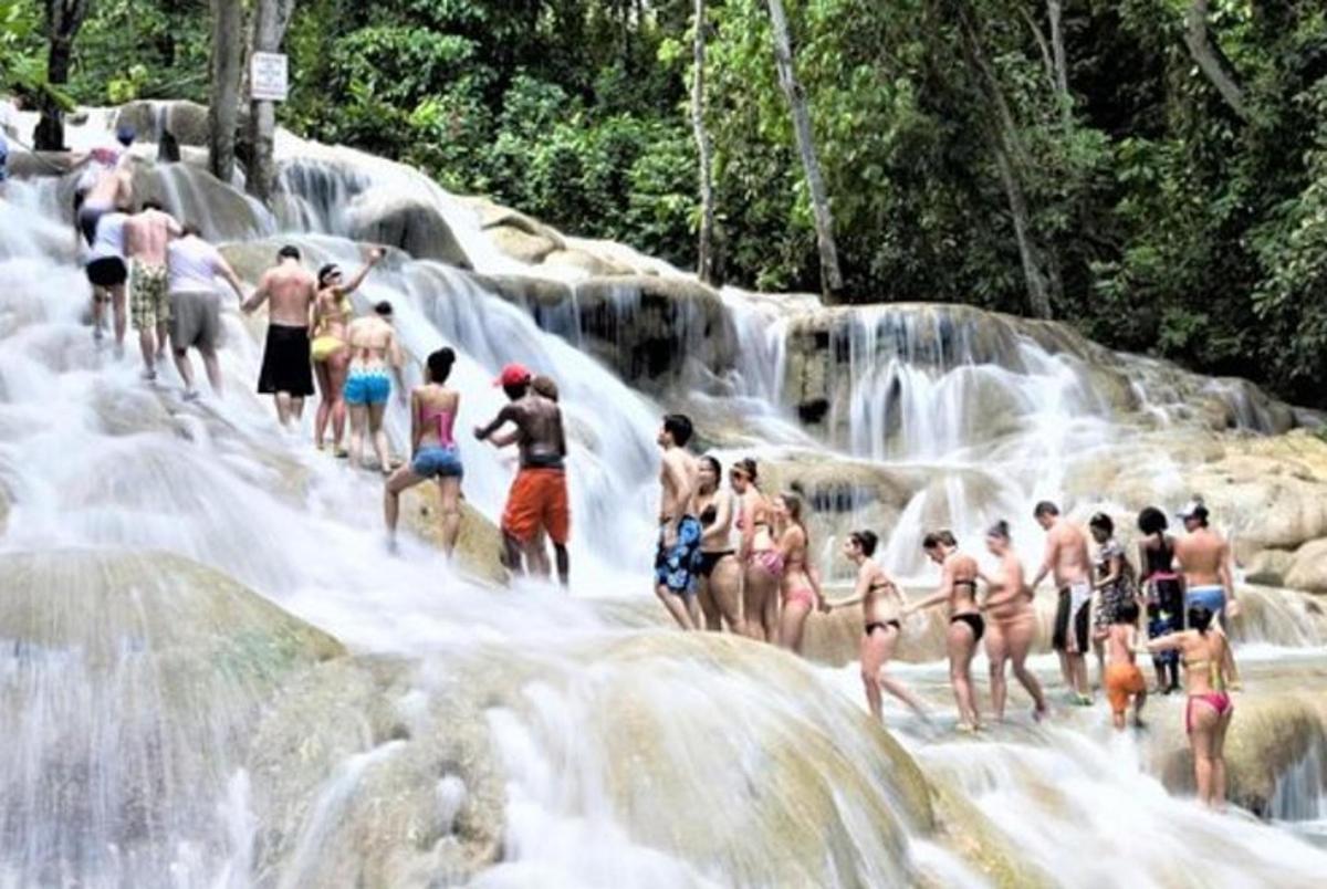 um grupo de pessoas em pé em frente a uma cachoeira