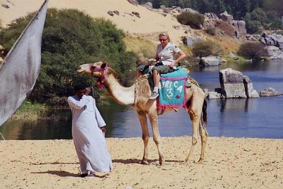 una donna che cavalca un cammello su una spiaggia accanto a un uomo