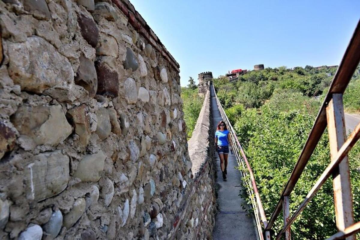 uma mulher caminhando em uma ponte ao lado de um muro de pedra