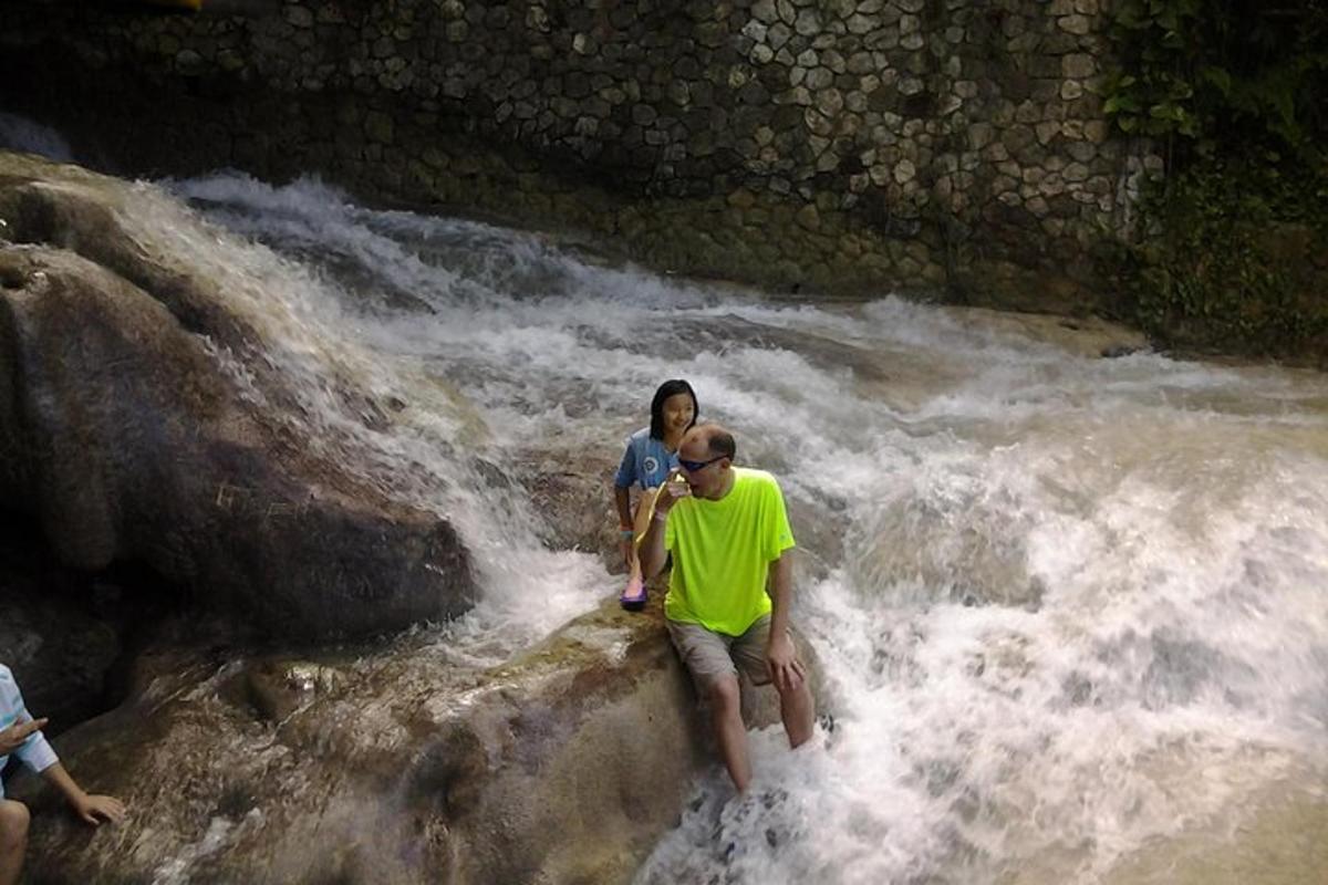 seorang lelaki dan seorang wanita berdiri di atas batu di sungai