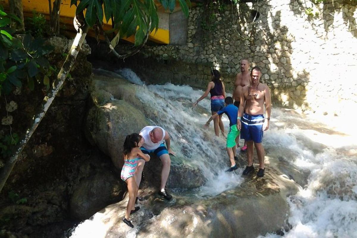 sekumpulan orang berdiri di dalam air terjun