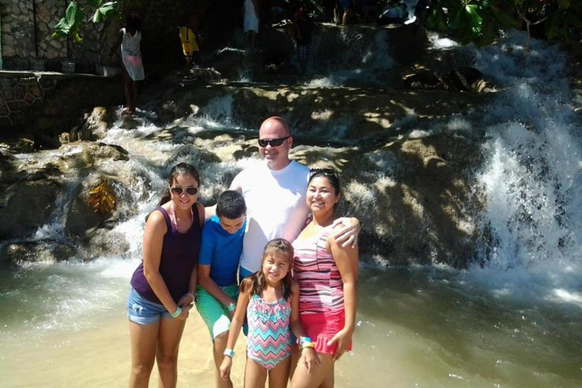 Una familia parada en la playa frente a una cascada.