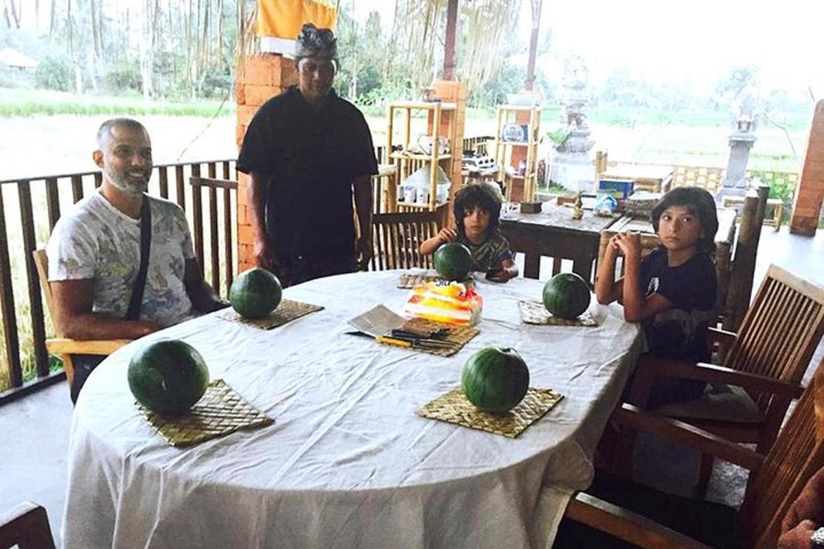 a group of people sitting around a table with watermelons on it