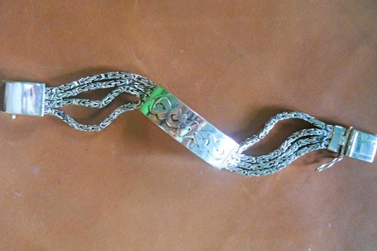 een zilveren armband met een ketting op een tafel
