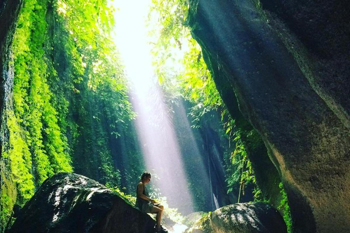 eine Person, die auf einem Felsen vor einem Wasserfall sitzt