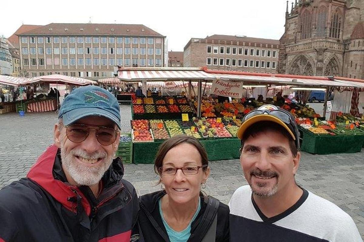 Dos hombres y una mujer de pie frente a un mercado