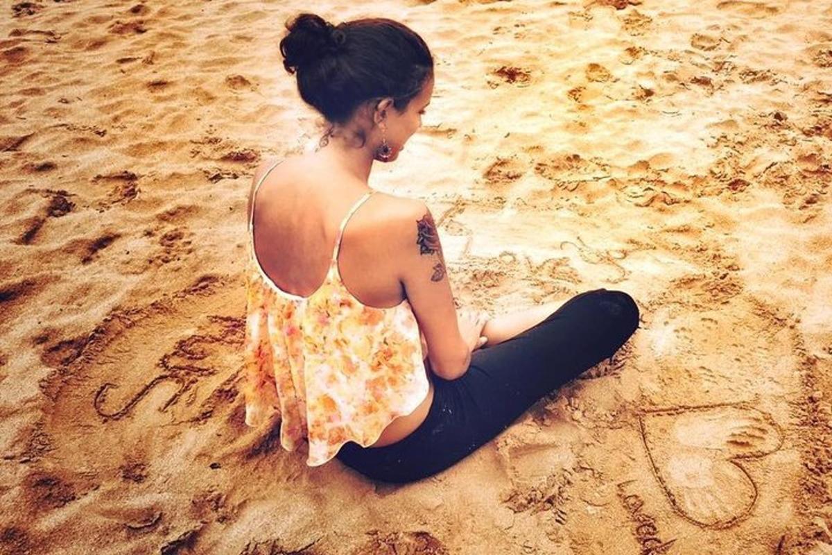 seorang wanita duduk di pantai di dalam pasir