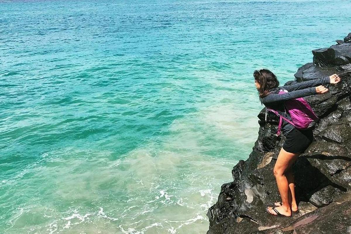 seorang wanita berdiri di atas batu berhampiran air