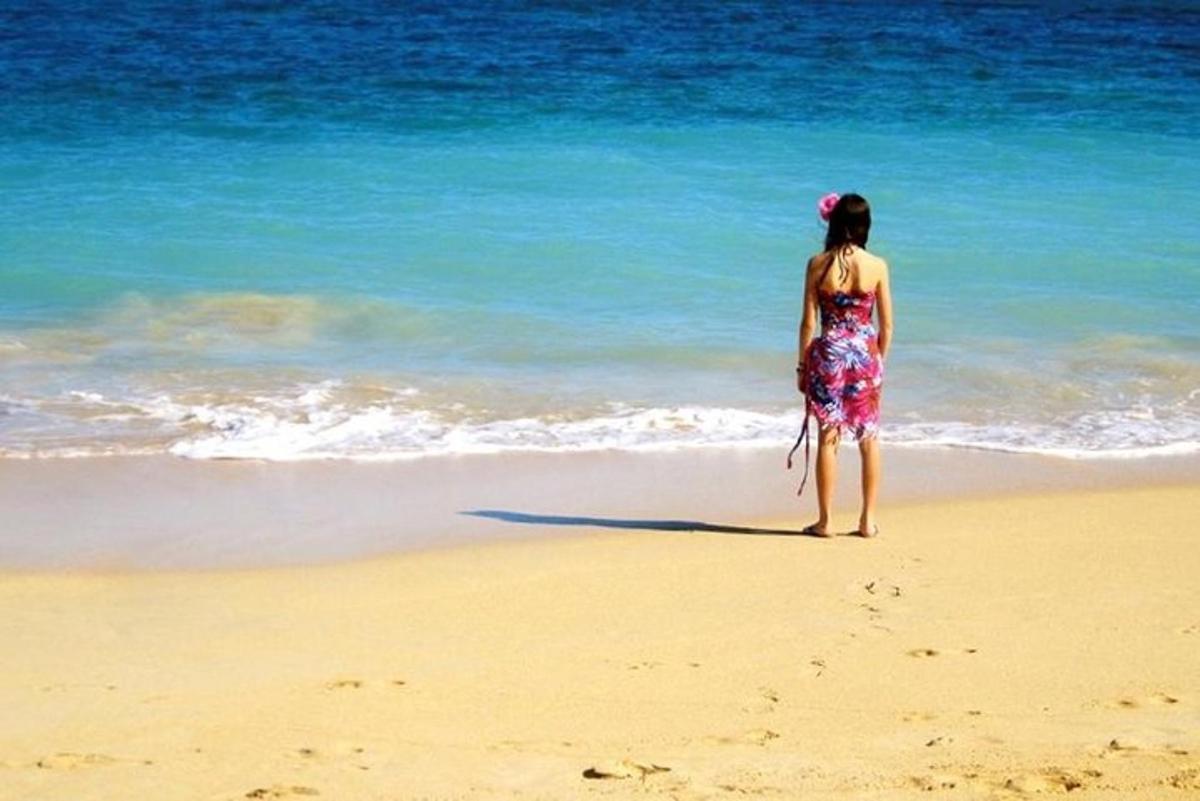 ženska, ki stoji na plaži in gleda v ocean