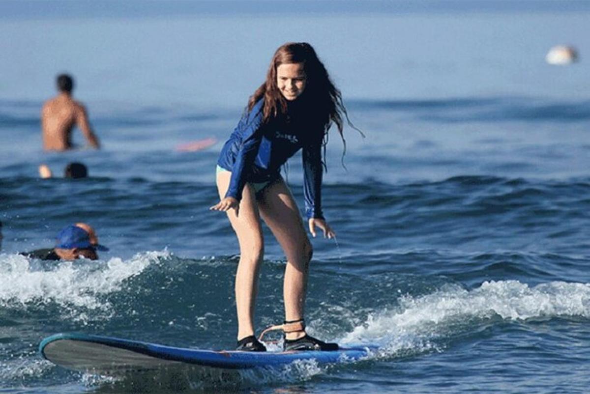a young girl riding a wave on a surfboard in the ocean