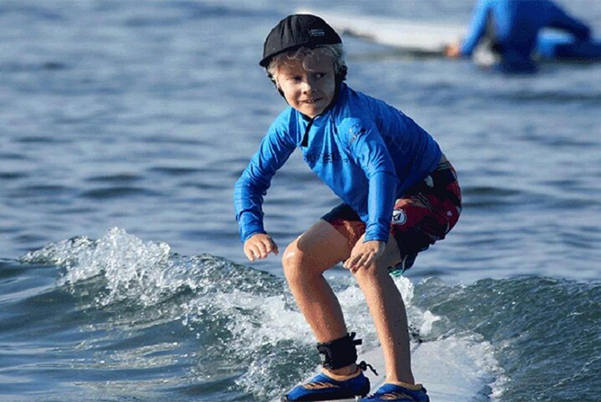 a young boy riding a wave on a surfboard
