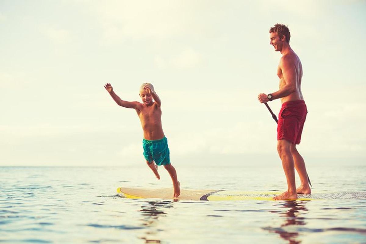 Dos hombres de pie sobre una tabla de surf en el agua
