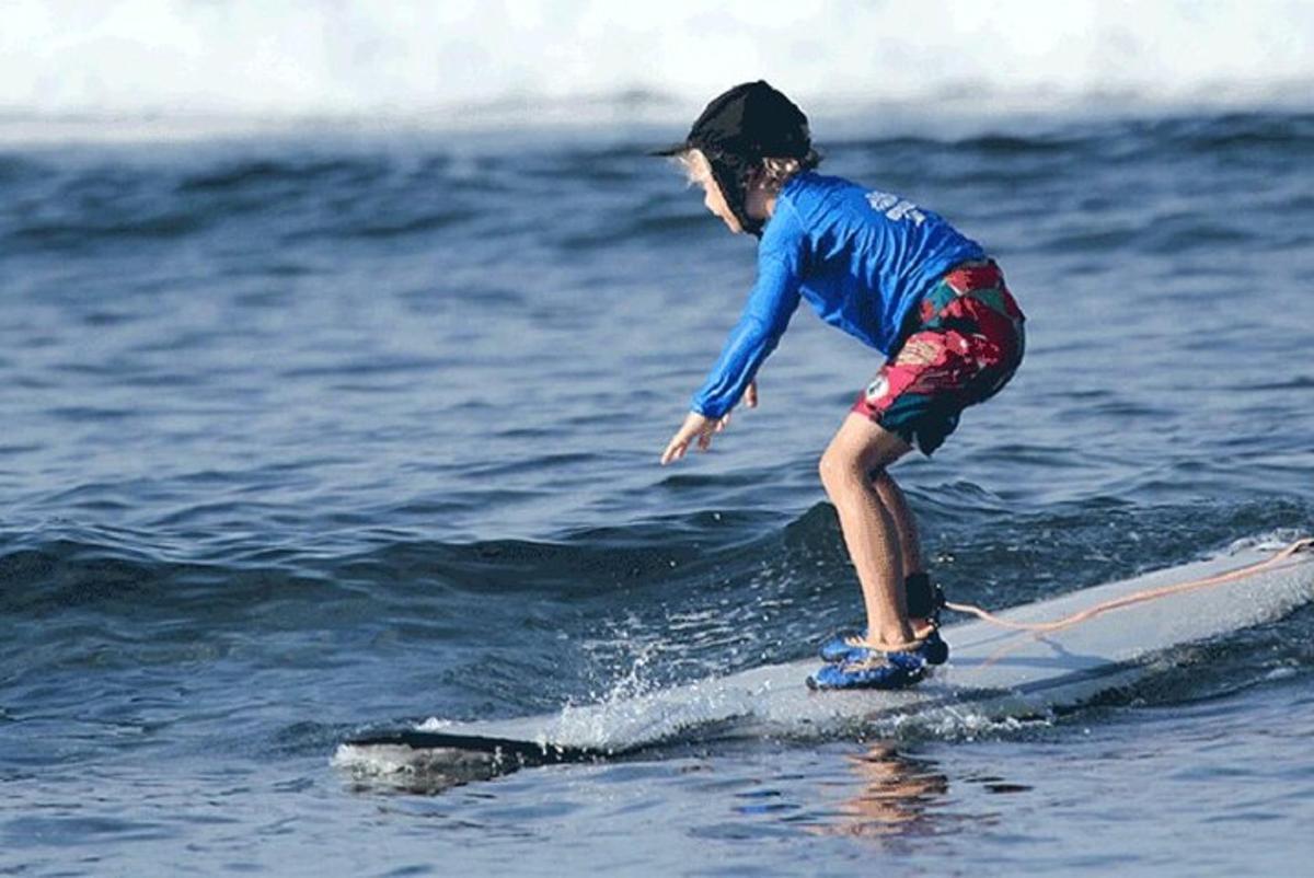 een jonge jongen die op een surfplank in de oceaan rijdt