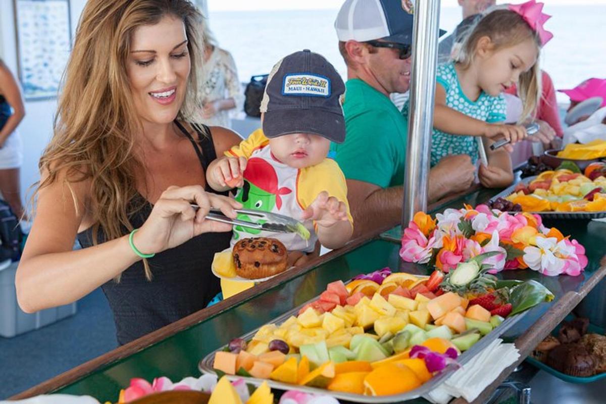 a woman holding a baby looking at a buffet of fruit