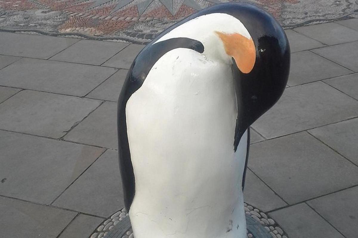 una statua di un pinguino in piedi su un marciapiede