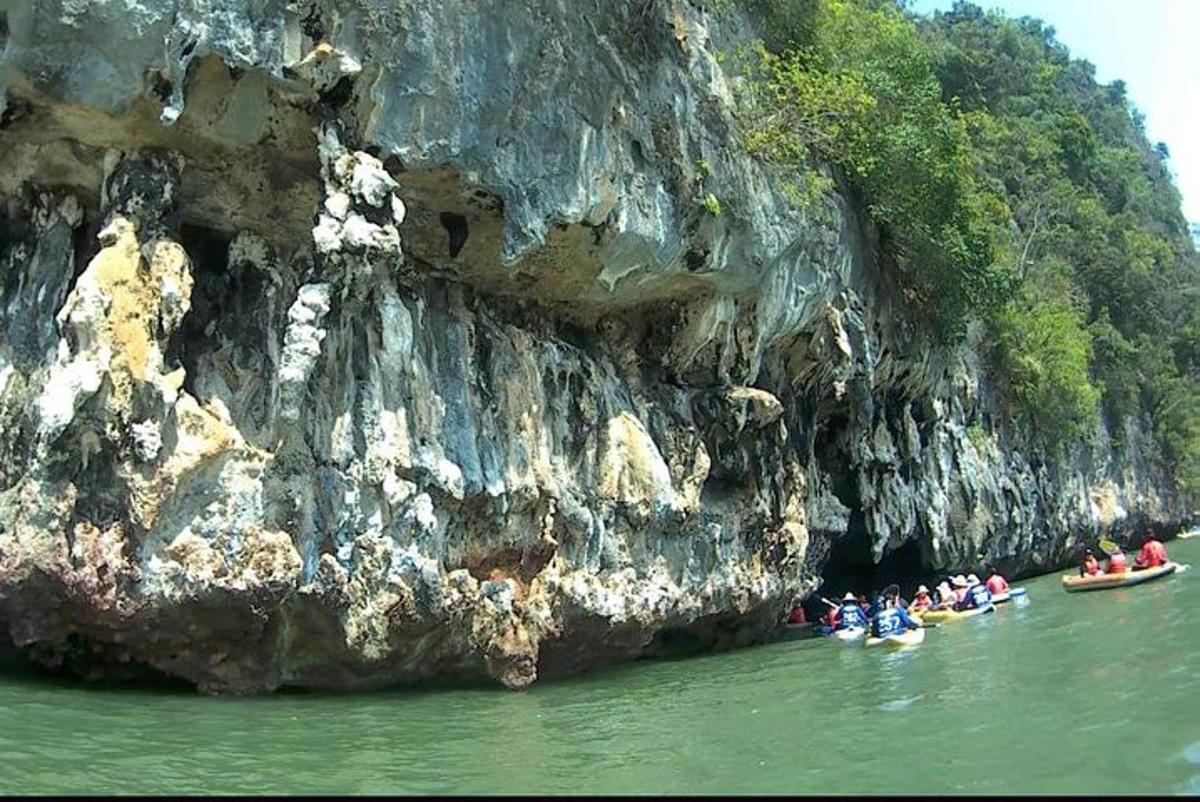 a group of people in boats in the water next to a cliff