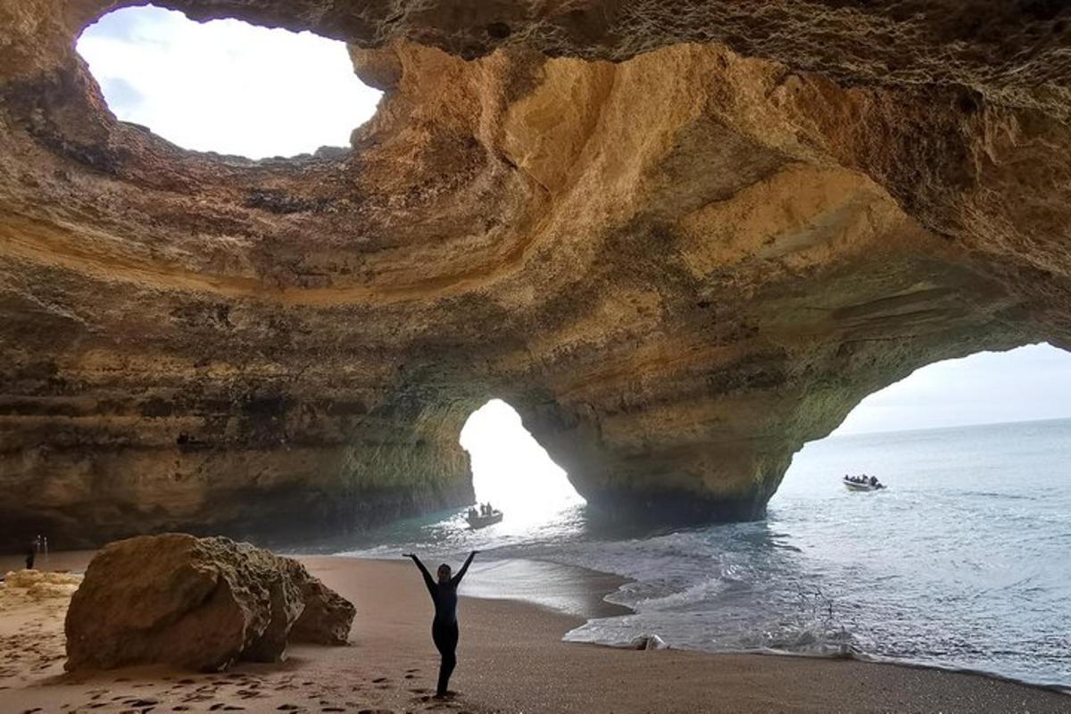 una persona in piedi di fronte a una grotta sulla spiaggia