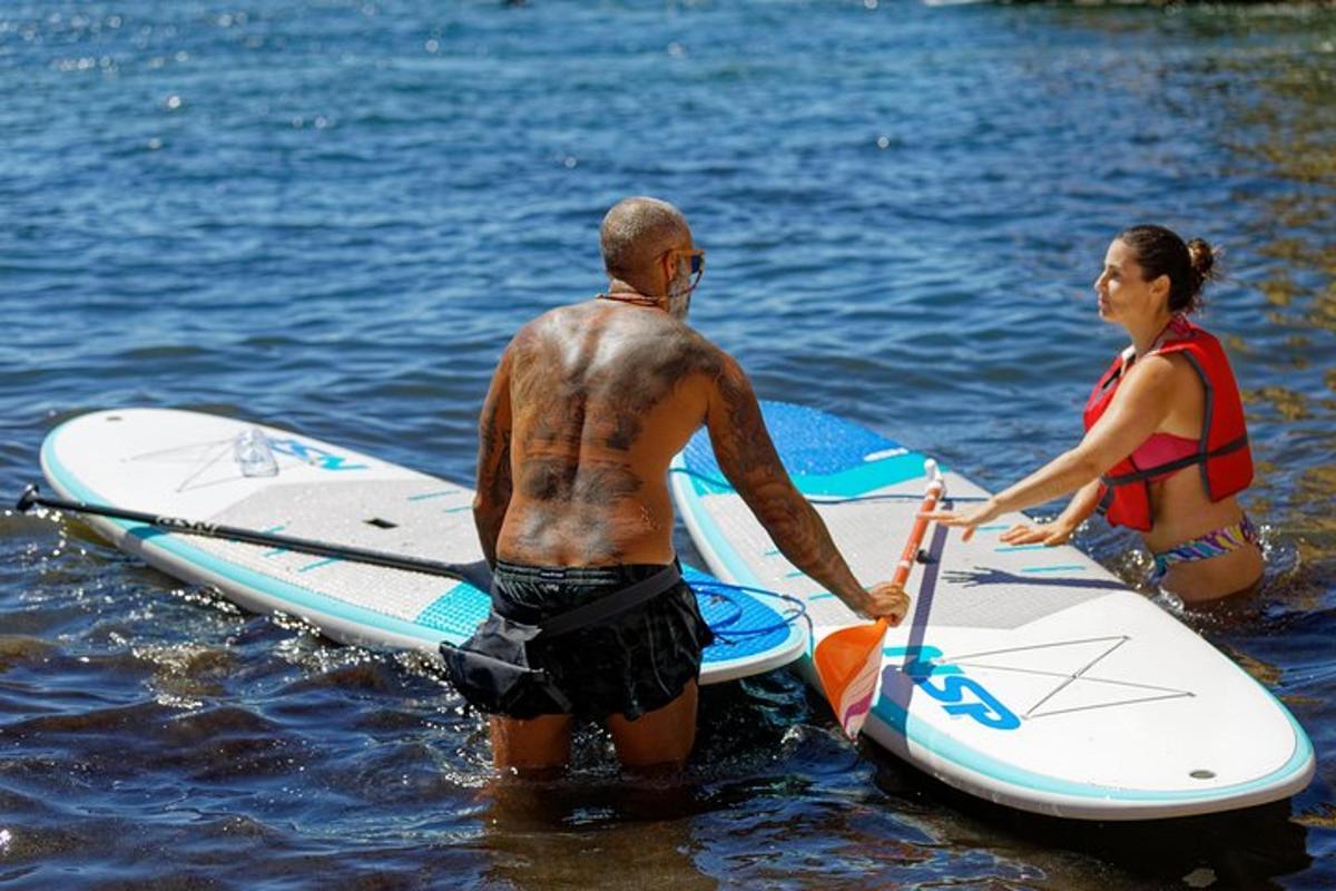 un uomo e una donna in piedi nell'acqua con le tavole da surf