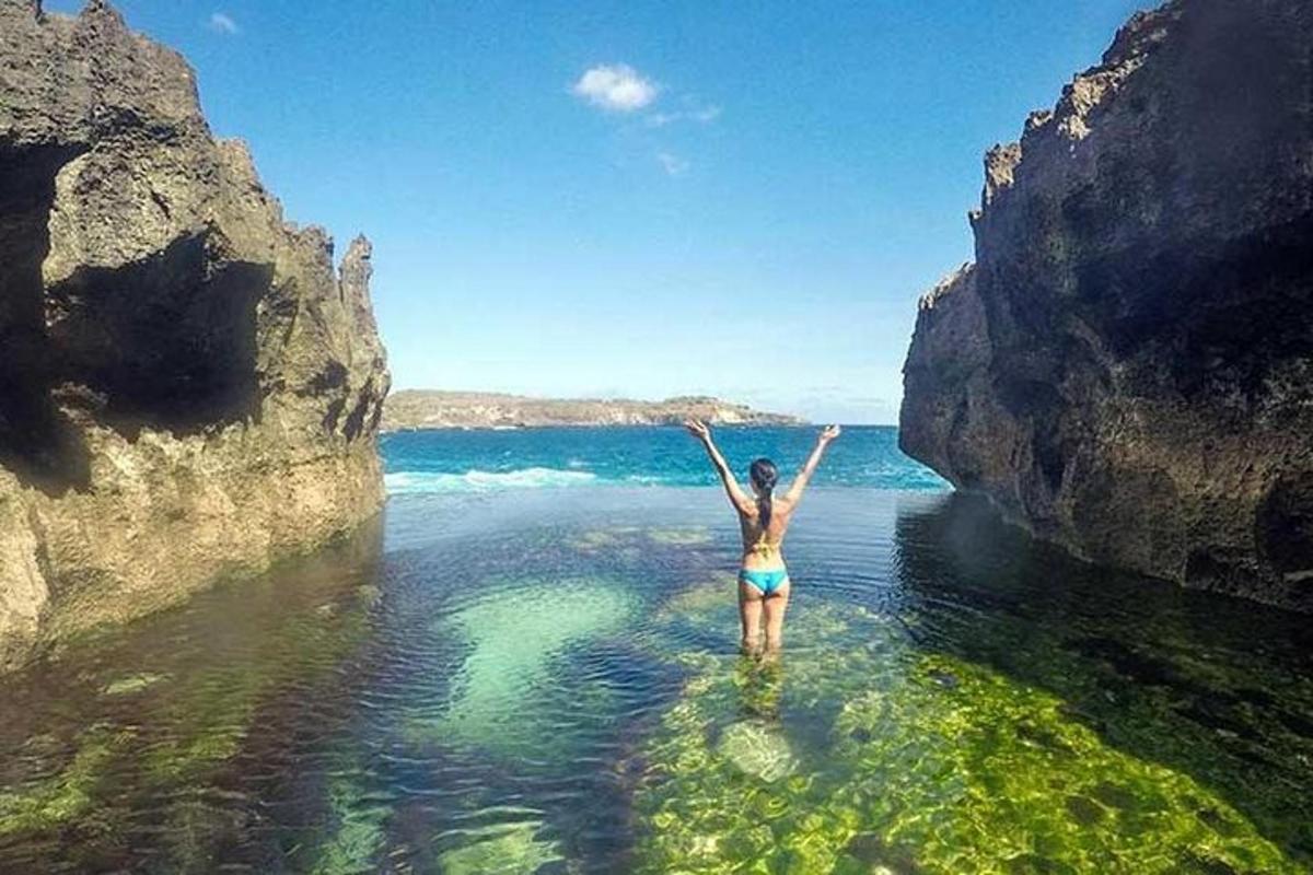 a woman standing in the water between two rocks
