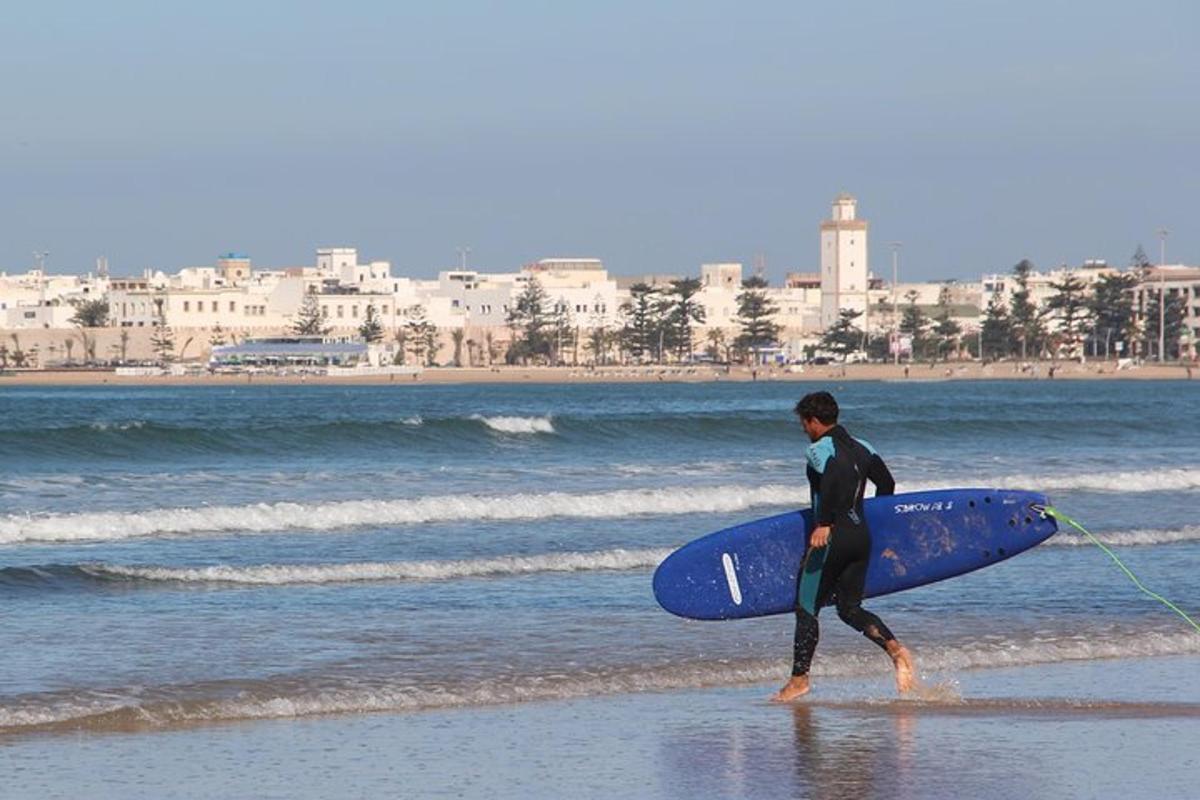 a man walking on the beach with a surfboard